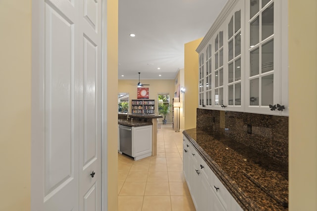 kitchen featuring light tile patterned floors, dishwasher, dark stone counters, white cabinets, and decorative backsplash