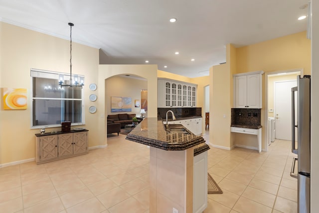 kitchen with kitchen peninsula, decorative backsplash, a breakfast bar area, white cabinetry, and sink