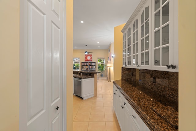 kitchen featuring decorative backsplash, white cabinets, light tile patterned floors, dark stone countertops, and dishwasher