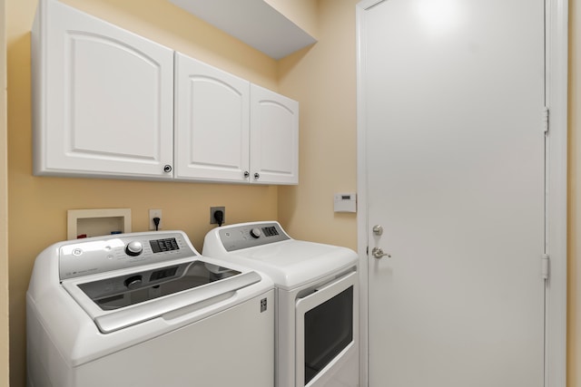 clothes washing area featuring washing machine and dryer and cabinets