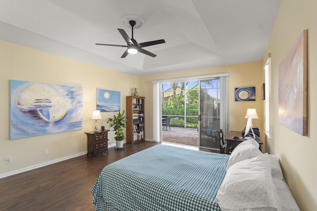 bedroom with dark hardwood / wood-style flooring, ceiling fan, access to outside, and a tray ceiling