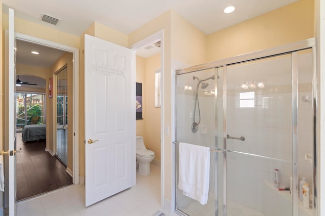 bathroom with toilet, walk in shower, wood-type flooring, and ceiling fan