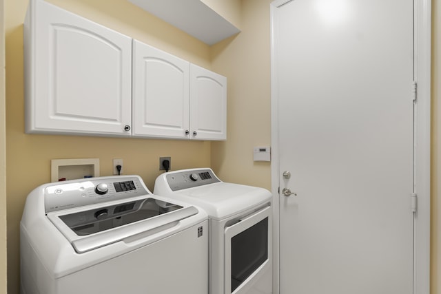 washroom with washing machine and dryer and cabinets