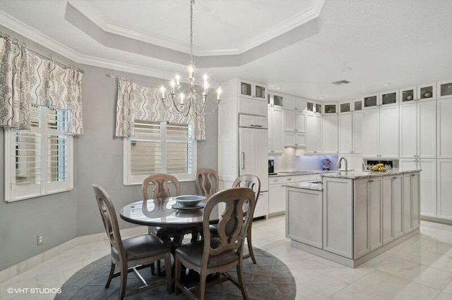 dining area with an inviting chandelier, a raised ceiling, and ornamental molding