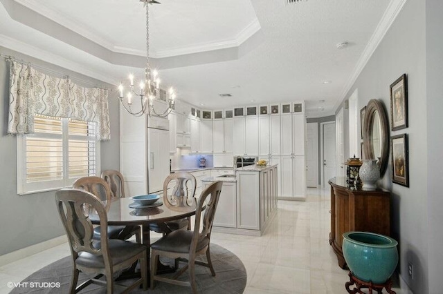 dining area with ornamental molding, an inviting chandelier, and a tray ceiling