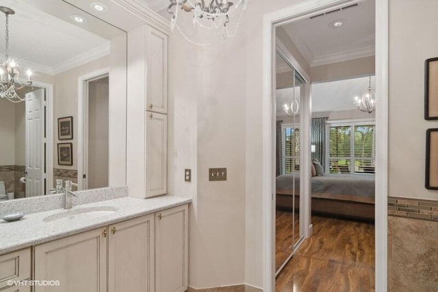 bathroom with wood-type flooring, vanity, a chandelier, and ornamental molding