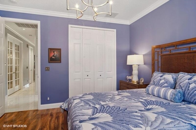 bedroom with an inviting chandelier, a closet, dark hardwood / wood-style floors, and ornamental molding