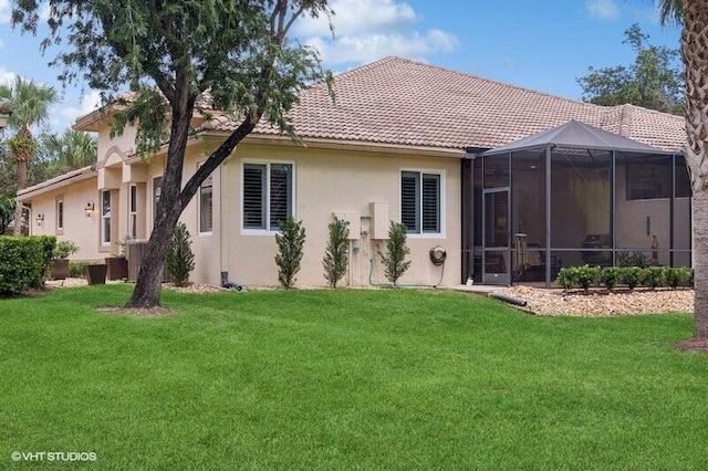 rear view of house with a lawn and a sunroom