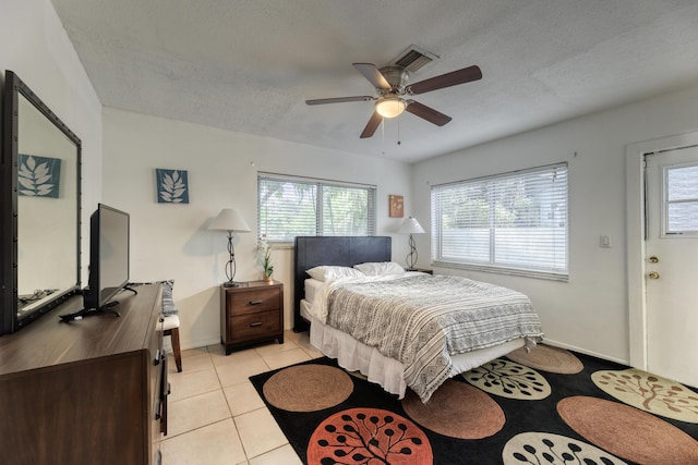 tiled bedroom with multiple windows, ceiling fan, and a textured ceiling