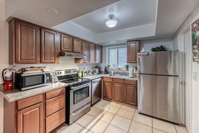 kitchen with a tray ceiling, sink, light tile patterned flooring, and appliances with stainless steel finishes