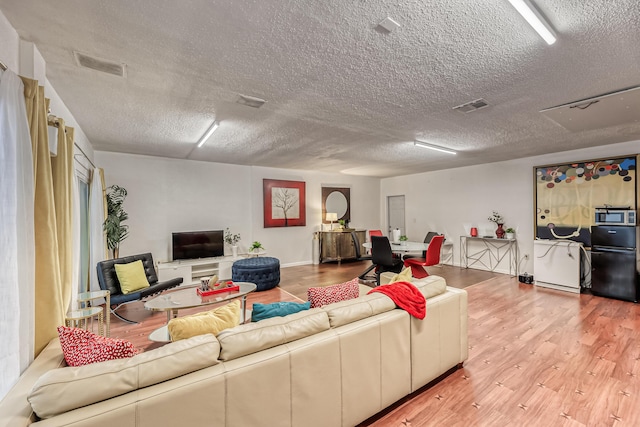 living room featuring a textured ceiling and light hardwood / wood-style floors