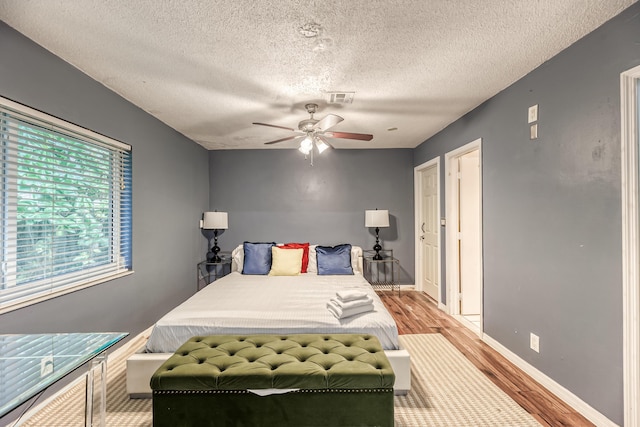 bedroom with a textured ceiling, light hardwood / wood-style floors, and ceiling fan