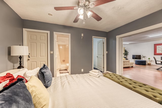 bedroom with ensuite bath, ceiling fan, wood-type flooring, and a textured ceiling