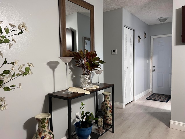 foyer entrance with a textured ceiling and light hardwood / wood-style floors