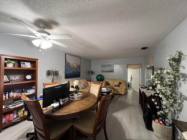 dining space with ceiling fan, a textured ceiling, and light wood-type flooring