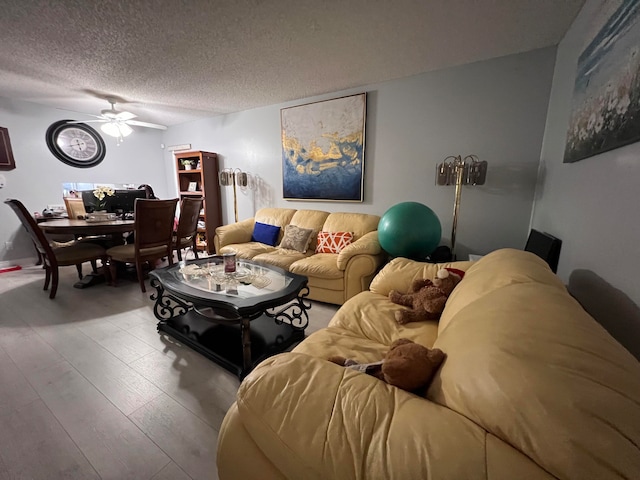 living room with ceiling fan, a textured ceiling, and light hardwood / wood-style floors