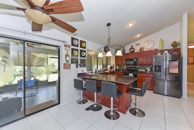 kitchen with black appliances, a breakfast bar area, lofted ceiling, decorative light fixtures, and light tile patterned floors