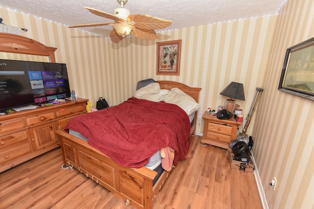 bedroom featuring light hardwood / wood-style flooring, a textured ceiling, and ceiling fan