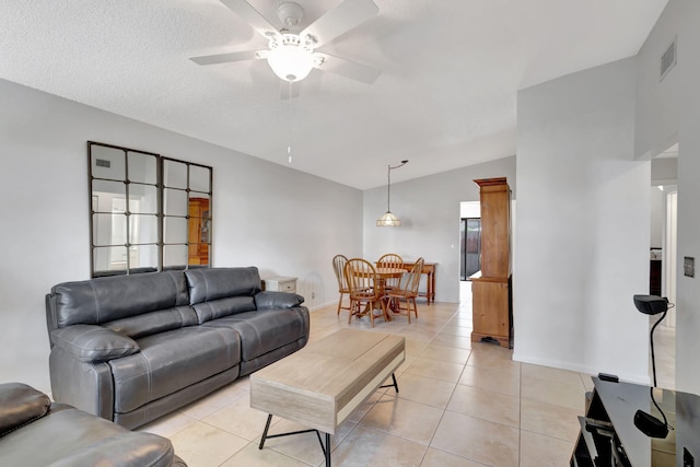 tiled living room featuring ceiling fan, a textured ceiling, and vaulted ceiling