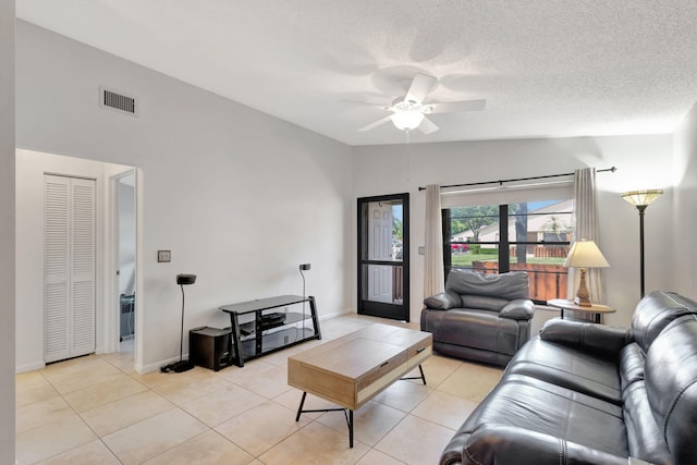 living room featuring vaulted ceiling, ceiling fan, light tile patterned floors, and a textured ceiling