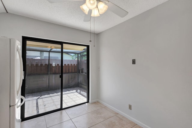 tiled empty room featuring ceiling fan and a textured ceiling