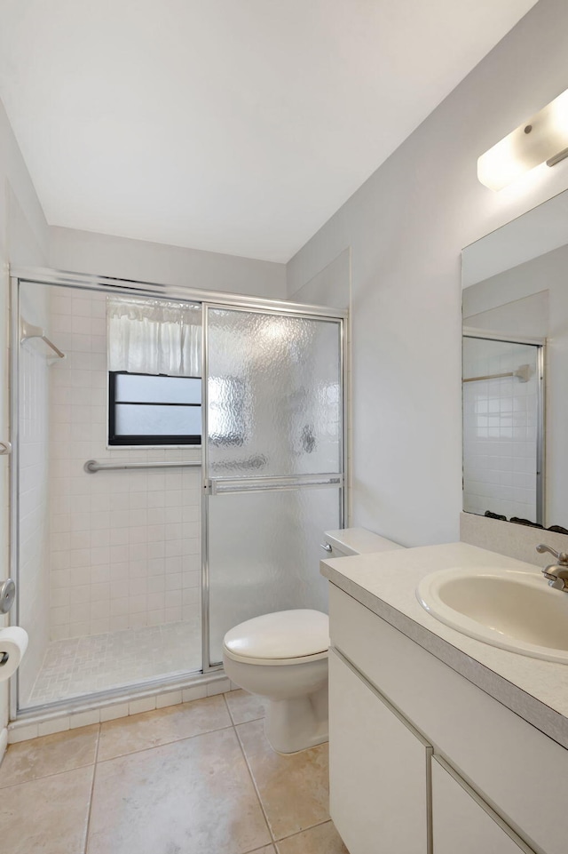 bathroom with tile patterned flooring, an enclosed shower, vanity, and toilet