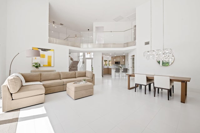 tiled living room with a high ceiling and a chandelier