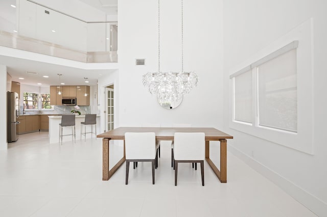 tiled dining area featuring a notable chandelier and a towering ceiling