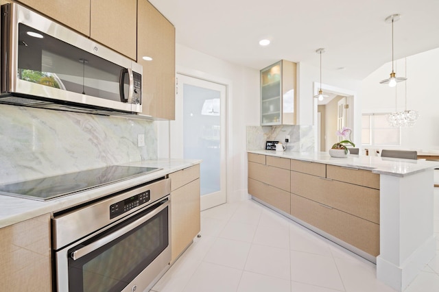 kitchen with stainless steel appliances, decorative backsplash, light brown cabinets, and hanging light fixtures