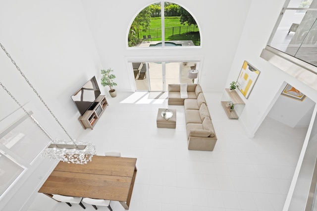 living room with a high ceiling, tile patterned flooring, an inviting chandelier, and plenty of natural light