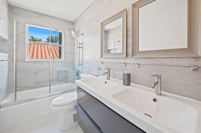 full bathroom featuring tasteful backsplash, toilet, tile walls, bath / shower combo with glass door, and vanity