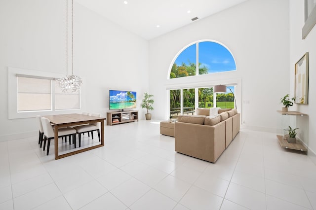 living room with a high ceiling, an inviting chandelier, and light tile patterned floors