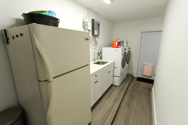 laundry area with separate washer and dryer, light hardwood / wood-style floors, sink, and cabinets