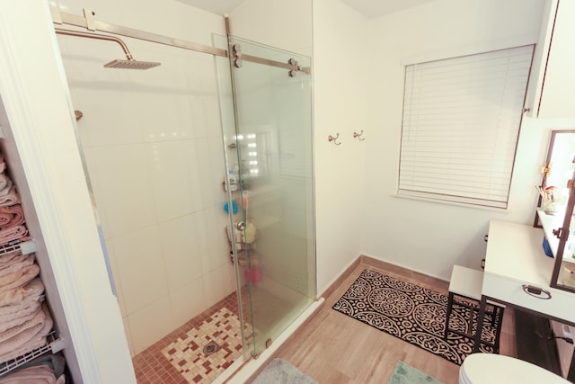 bathroom with hardwood / wood-style flooring, toilet, and an enclosed shower