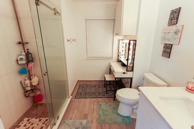 bathroom with hardwood / wood-style flooring, vanity, toilet, and a shower with shower door