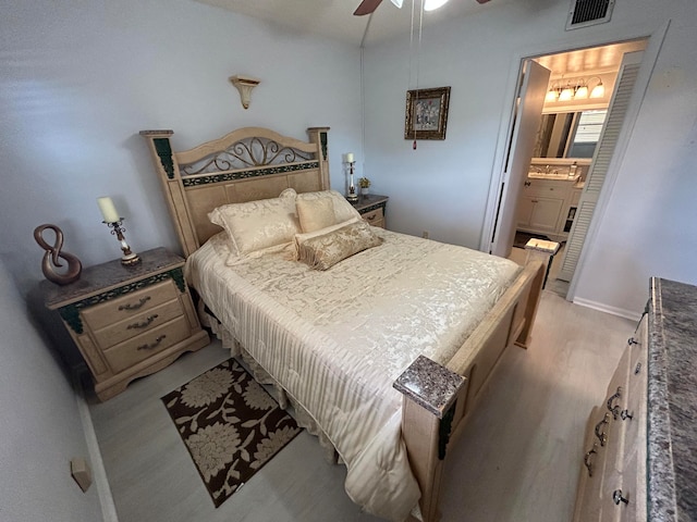 bedroom with light hardwood / wood-style floors, connected bathroom, sink, and ceiling fan