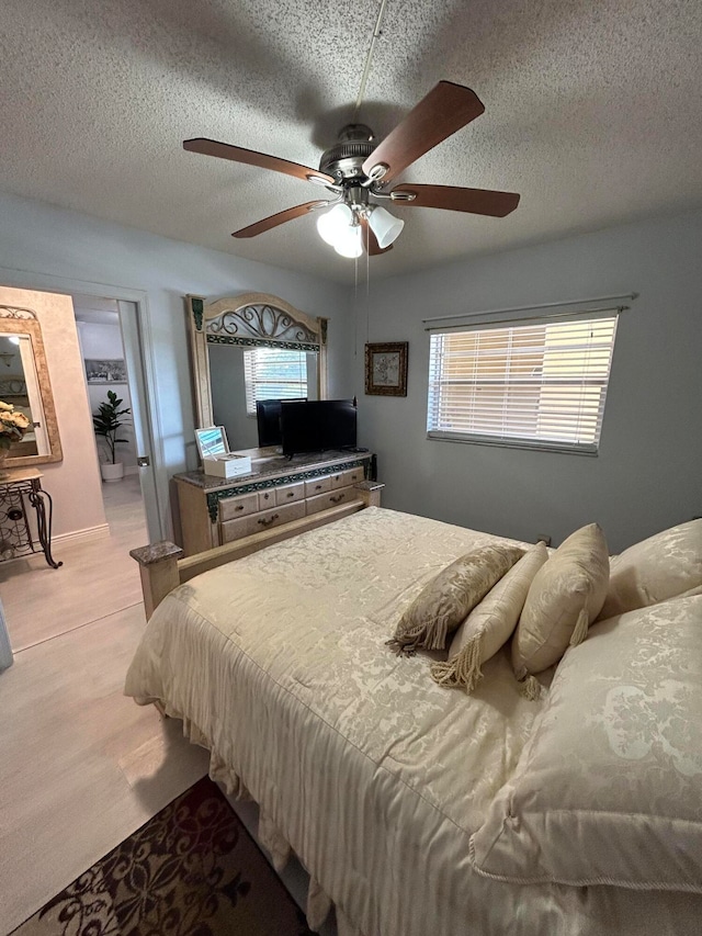 carpeted bedroom featuring ceiling fan, multiple windows, and a textured ceiling