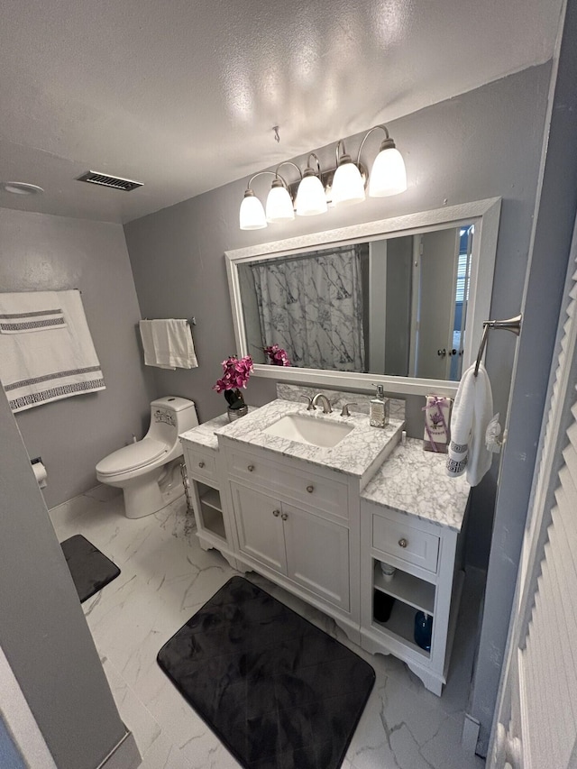 bathroom featuring a textured ceiling, vanity, and toilet