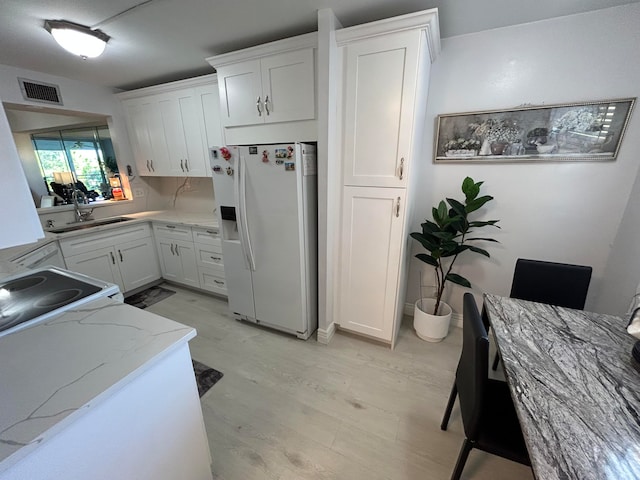 kitchen featuring light hardwood / wood-style floors, white refrigerator with ice dispenser, sink, white cabinets, and light stone countertops