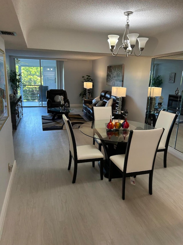 dining area with a notable chandelier, wood-type flooring, and a textured ceiling