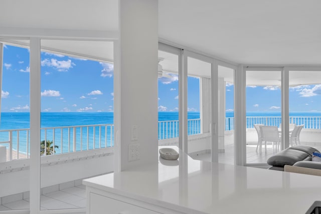 unfurnished sunroom featuring a view of the beach, a water view, and a wealth of natural light