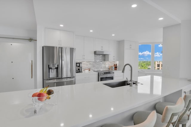 kitchen with tasteful backsplash, a breakfast bar area, sink, stainless steel appliances, and white cabinets