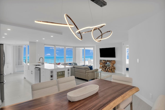 dining area featuring sink, light hardwood / wood-style flooring, a chandelier, and a healthy amount of sunlight