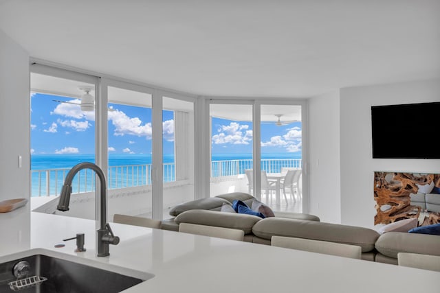 living room featuring a water view, expansive windows, sink, and a healthy amount of sunlight