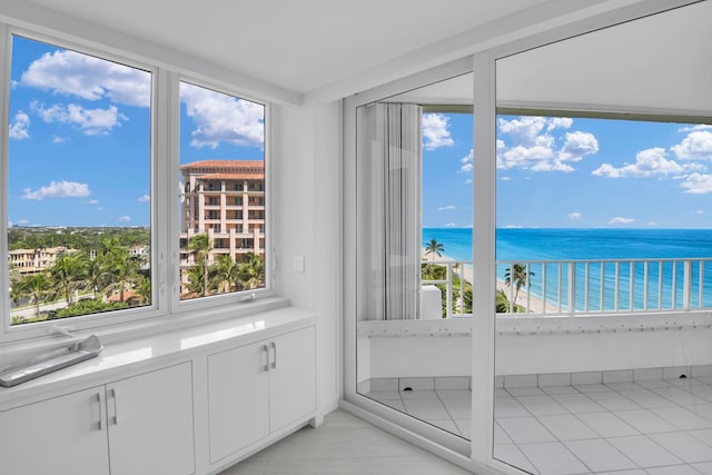 unfurnished sunroom with a water view and a view of the beach