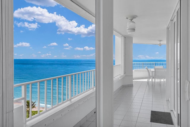 balcony featuring ceiling fan, a beach view, and a water view