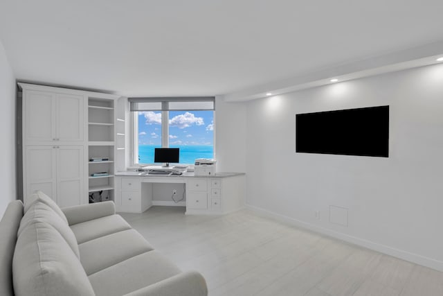 living room featuring light wood-type flooring, built in desk, and expansive windows