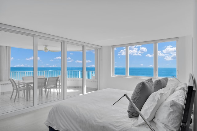 bedroom featuring access to outside, a view of the beach, floor to ceiling windows, light hardwood / wood-style floors, and a water view