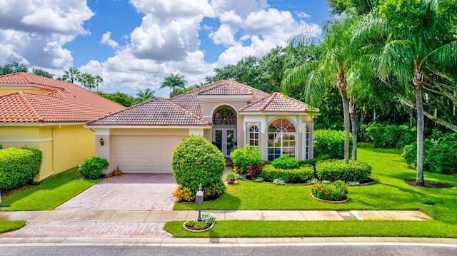 mediterranean / spanish-style house with decorative driveway, a tile roof, stucco siding, an attached garage, and a front yard