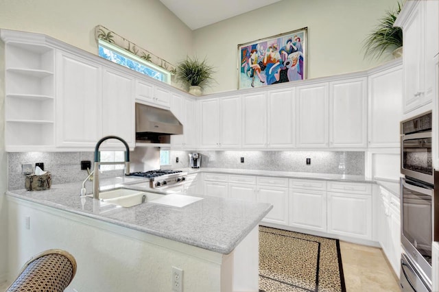 kitchen with decorative backsplash, white cabinets, a sink, a peninsula, and under cabinet range hood